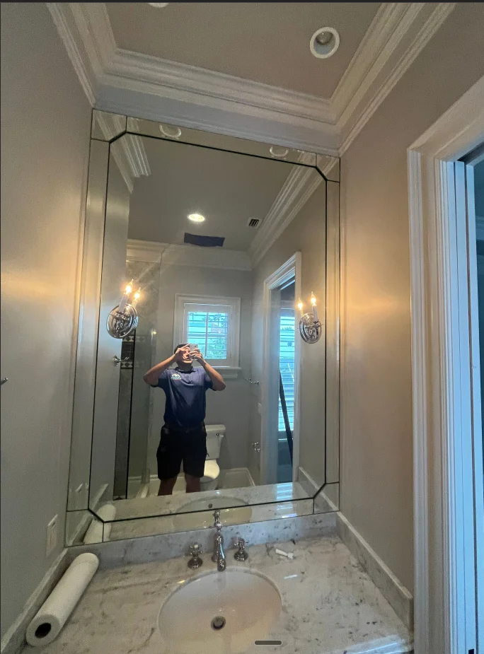 Newly painted bathroom with crown molding, marble vanity, and framed mirror