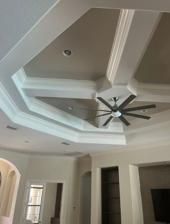 White coffered ceiling with recessed lights and black ceiling fan in Naples home