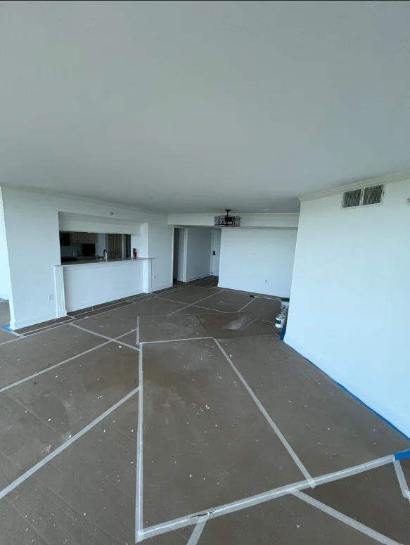 Interior room with white drywall walls and plastic floor protection during painting preparation