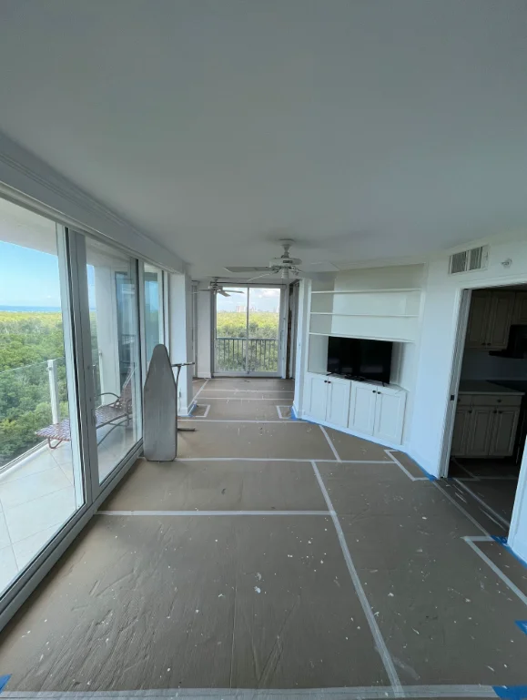Freshly painted condo interior with white walls, built-in TV cabinet, and floor protection during painting project