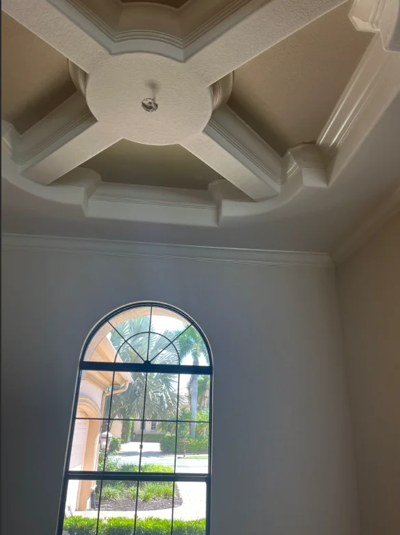 Coffered ceiling with white trim and painted arched window in Naples home