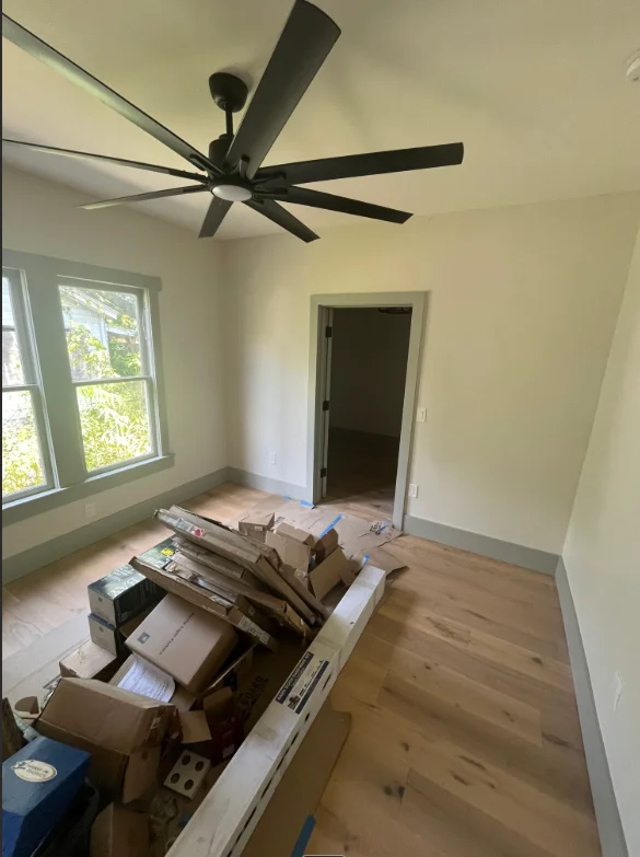 Newly painted room with black ceiling fan and natural wood flooring in Naples home