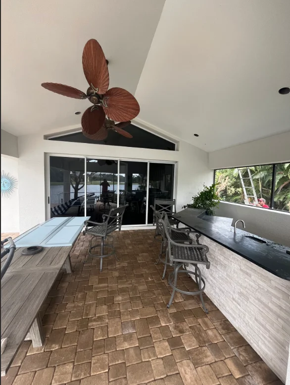 Bright covered patio with white painted ceiling, dark trim, and decorative ceiling fan