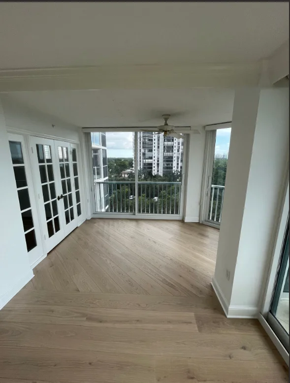 Bright white painted condo interior with wood flooring, glass doors, and city views