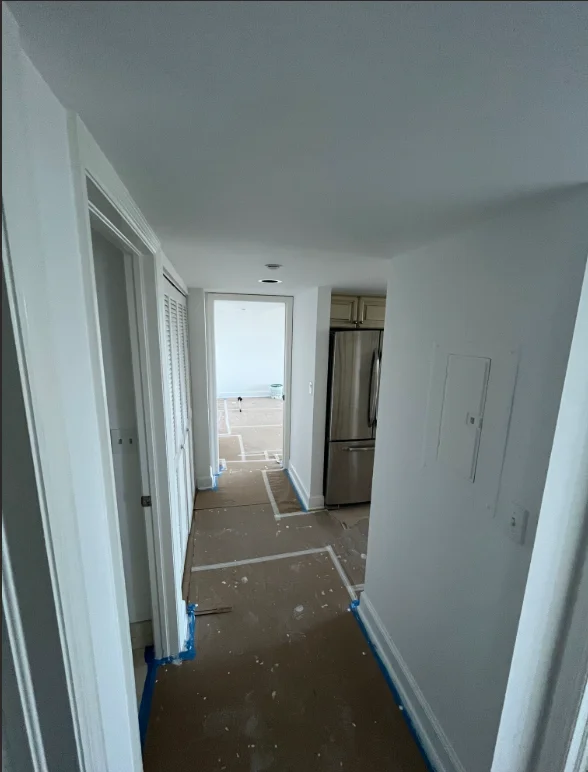 Freshly painted white hallway with drywall finishing, stainless steel refrigerator, and ocean view