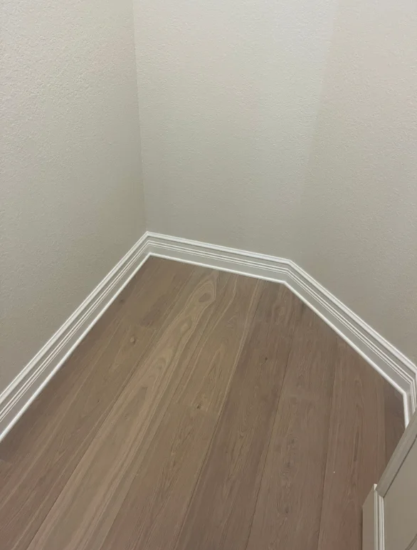 Newly painted interior corner with cream walls and white trim baseboards