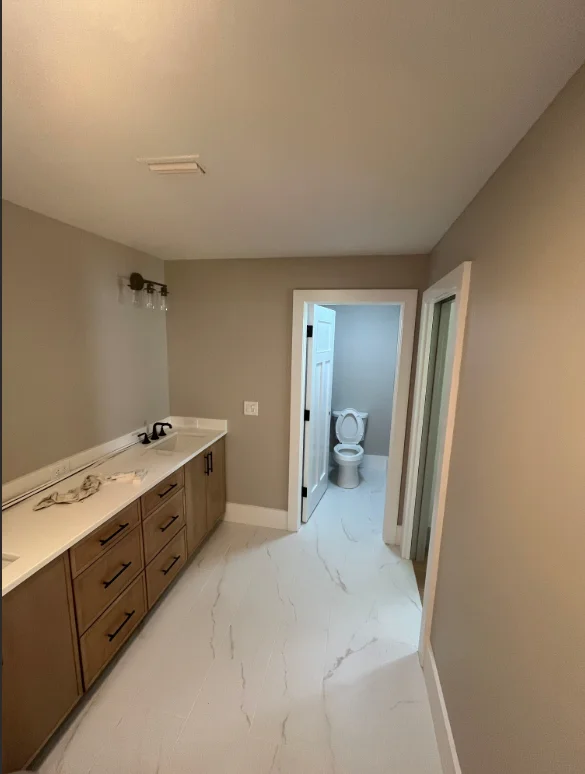 Master bathroom with neutral painted walls, wood vanity, and marble tile flooring