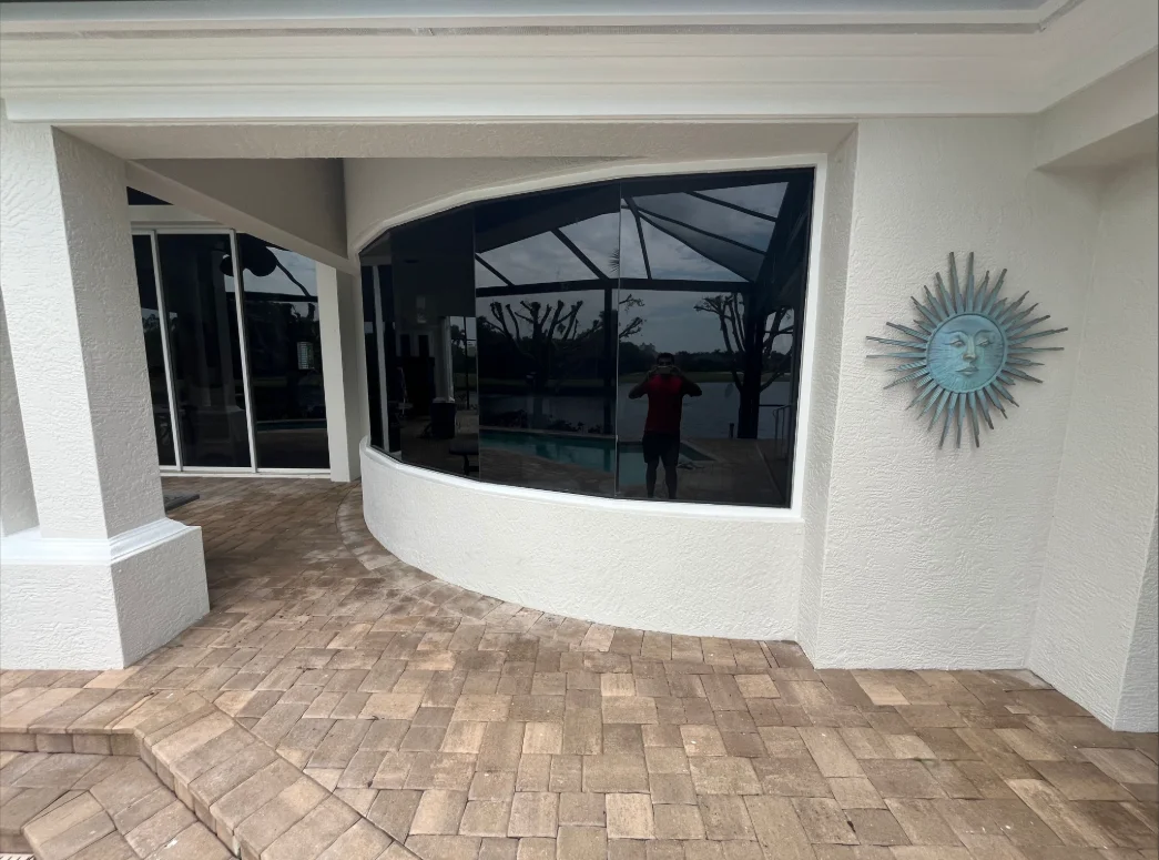 White painted lanai with curved walls, dark-framed glass windows, and brick paver flooring