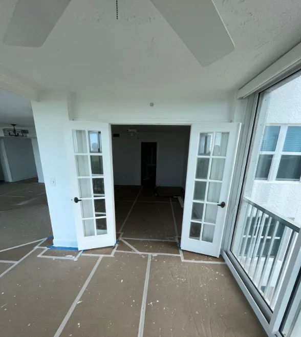 Interior room with white painted walls, ceiling, and French doors during painting project completion