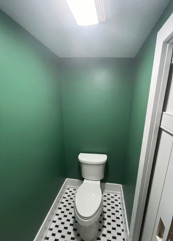 Bathroom with sage green walls, white ceiling, and black-white checkered floor