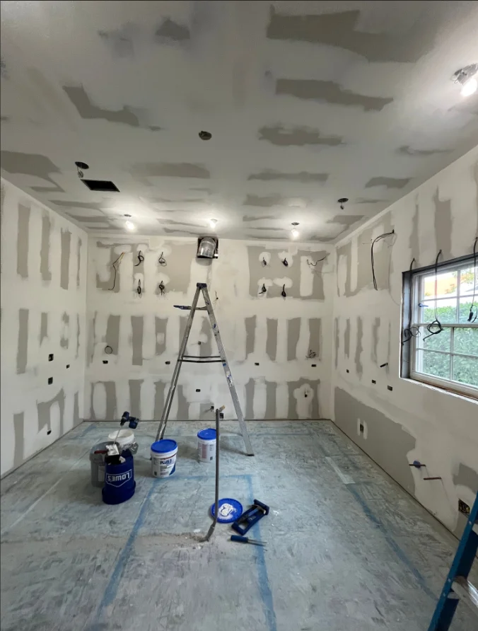 Interior room with drywall preparation, taped seams, and recessed lighting installation in progress