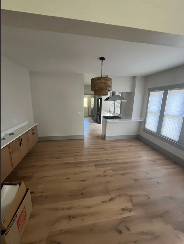 Freshly painted open-concept kitchen with white walls, wood floors, and pendant lighting