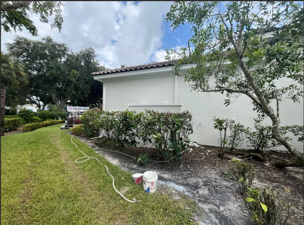 White painted residential home exterior with landscaping and mature trees in Naples