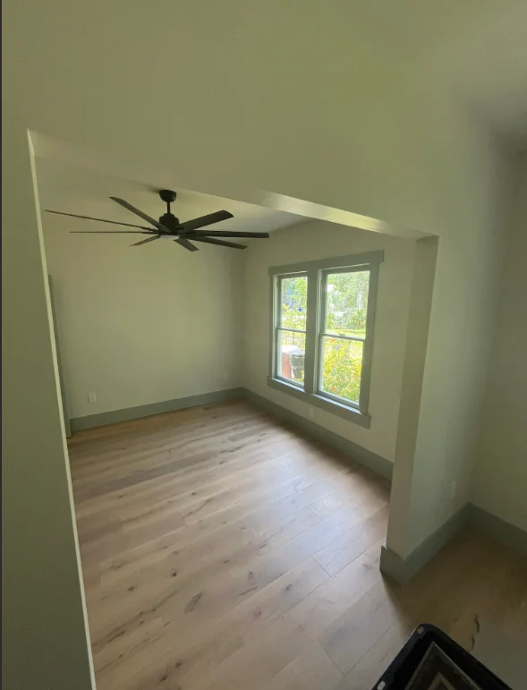 Newly painted interior room with sage green walls, white ceiling, and light wood flooring