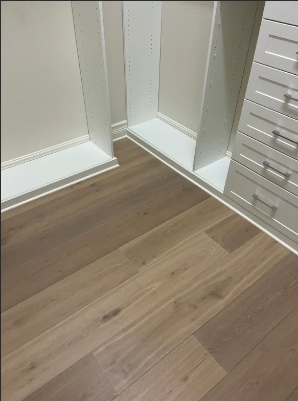 White painted closet interior with shelving units and wood flooring