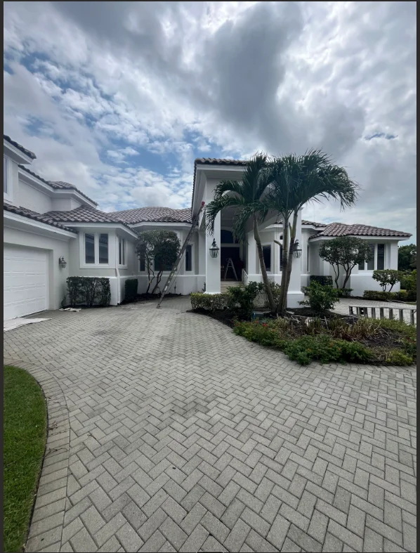 White stucco home with palm trees and paver driveway in Naples