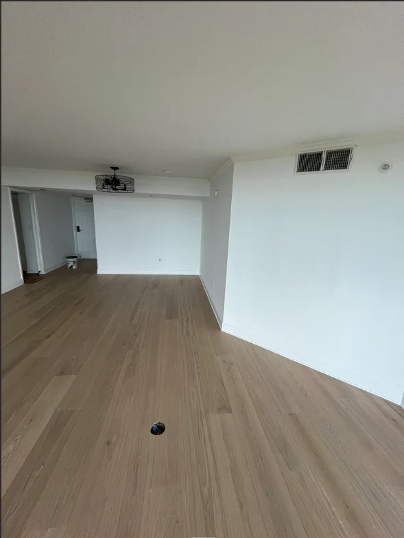 Freshly painted white drywall interior with wood flooring and ceiling vents