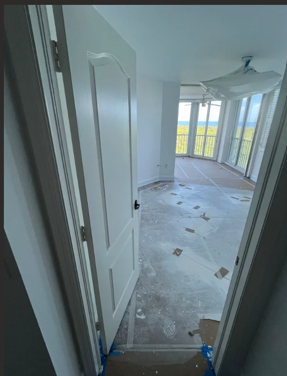 Interior room with white drywall, primed surfaces, and protective coverings ready for painting